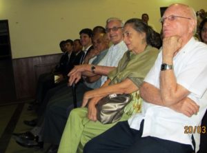 Clive smiles approvingly at the showing of the video seated next to him (left) is his wife Patsy and Father Gervais Girod a former Dean and to his right, former Principal Mervyn Moore