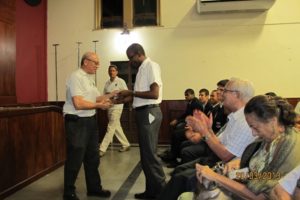 Peter Charles (Chair of the Class of ’75 Committee) presents a copy of the video to Father Gregory Augustine, Principal of Fatima College