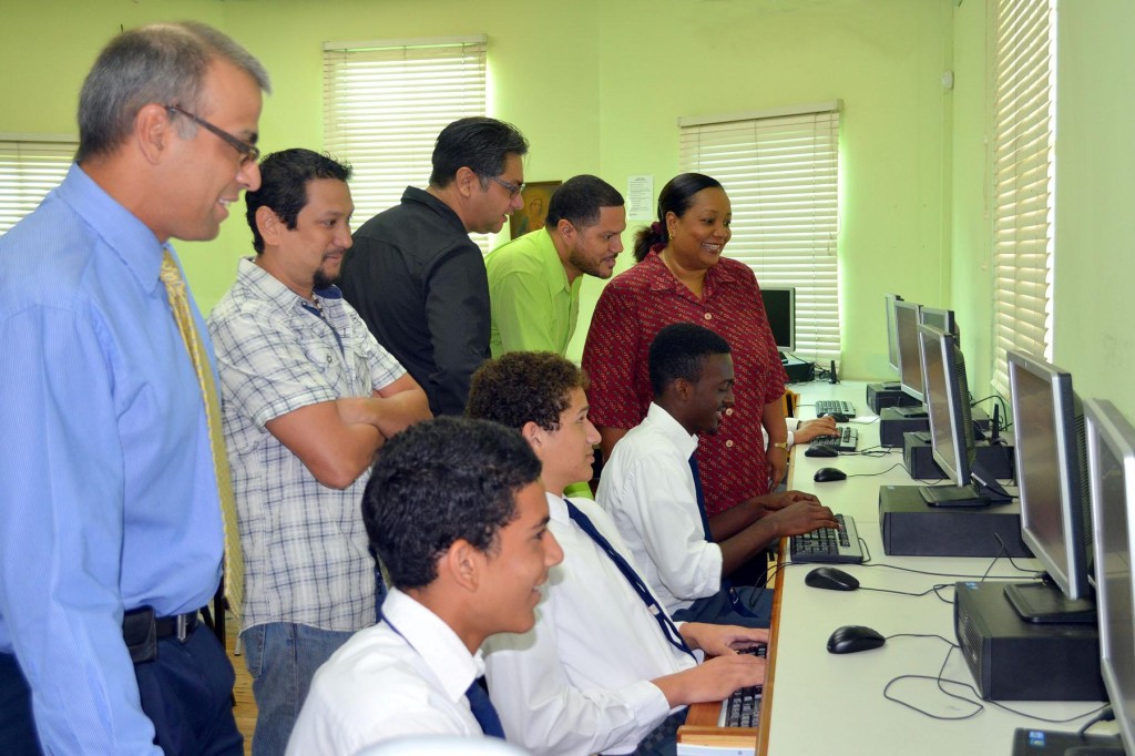 Members of the Class of ’86 Fundraising Committee look on as Form 6 enjoy the new computers under the watchful guidance of computer science instructor Ms. Moses.